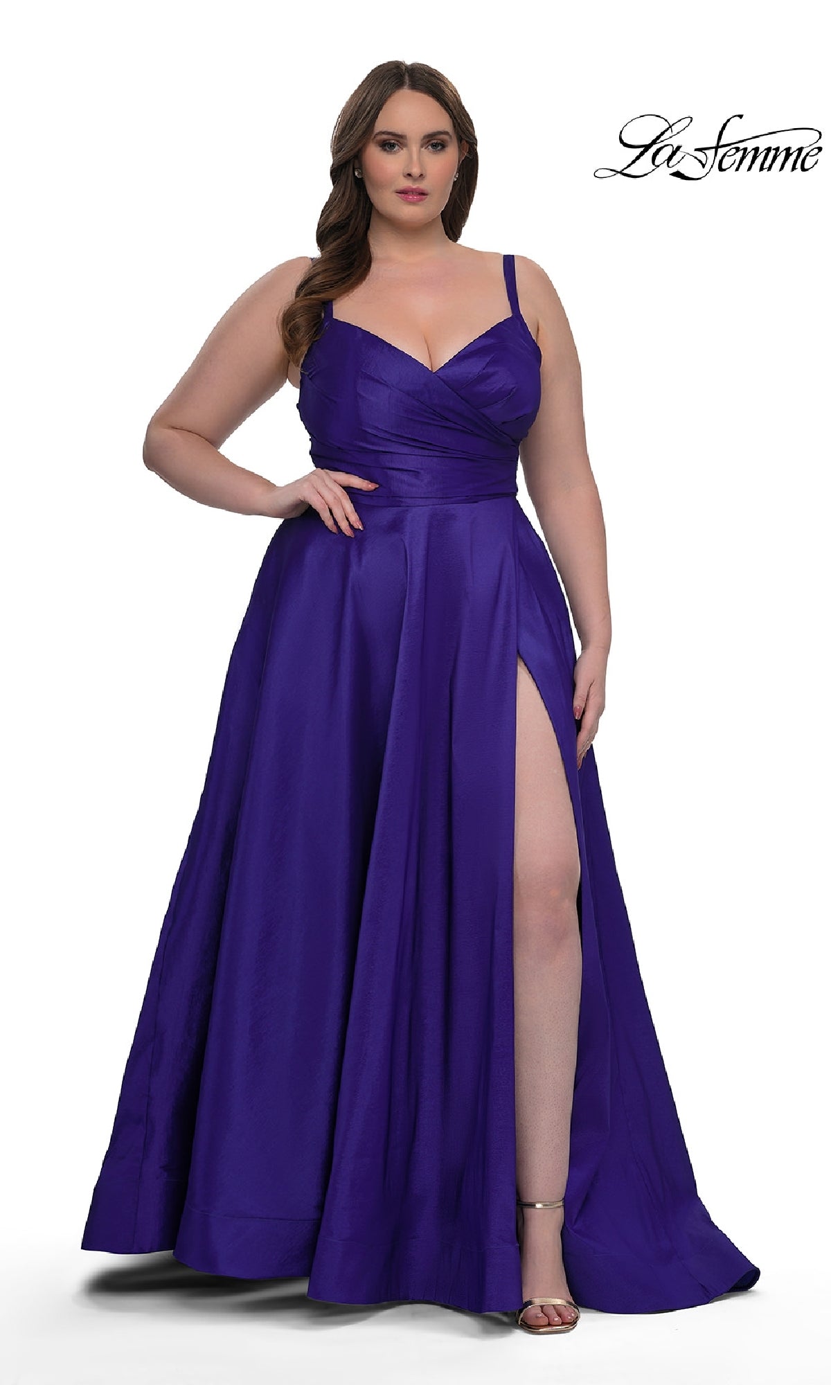 A woman models the Long Plus-Size Prom Dress La Femme 33075, a sleeveless, floor-length deep purple gown with an a-line skirt and faux-wrap v-neck, standing against a white background with the La Femme logo in the top right corner.